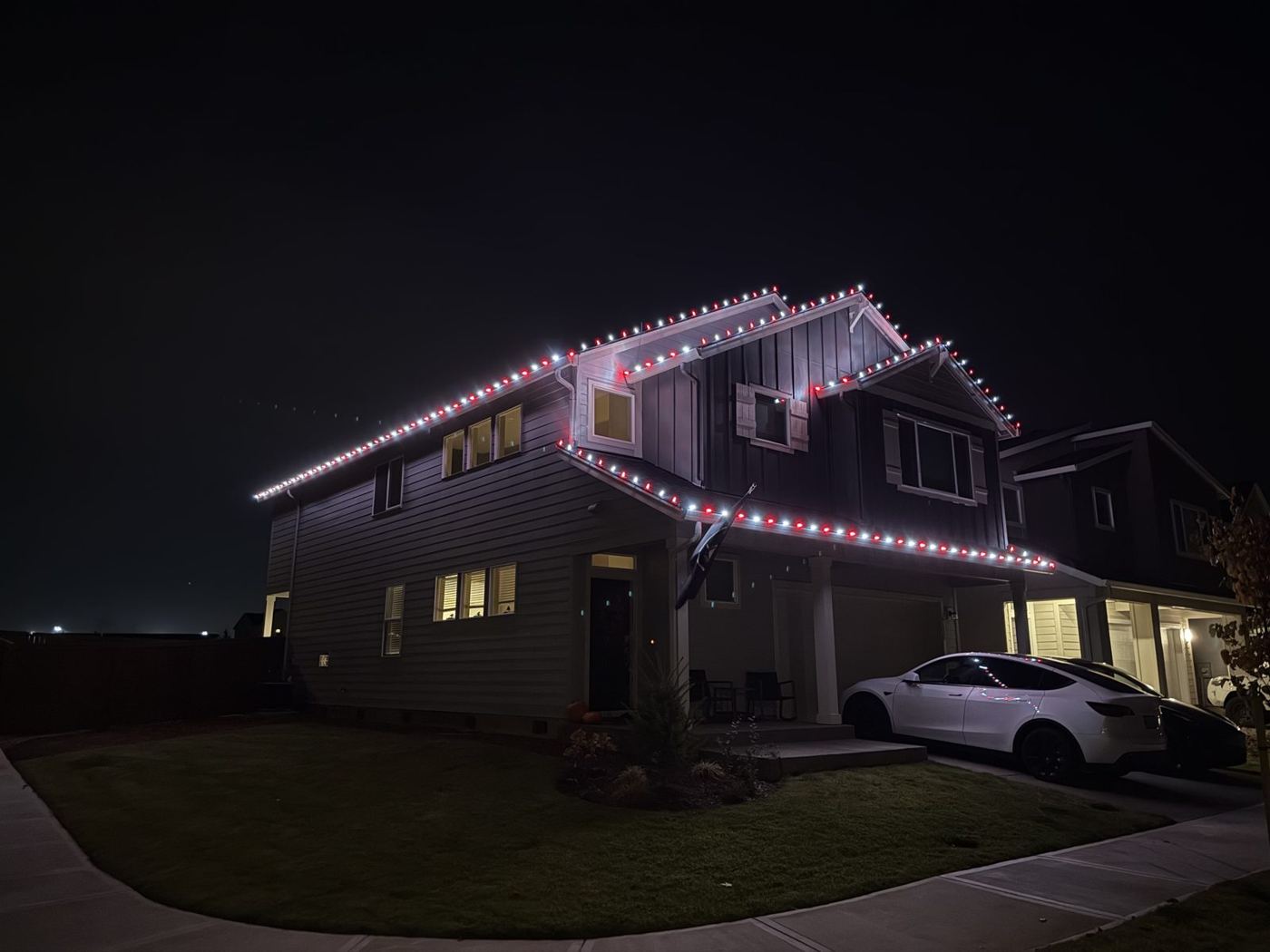 Multi-gable home lit in warm white on a rainy night