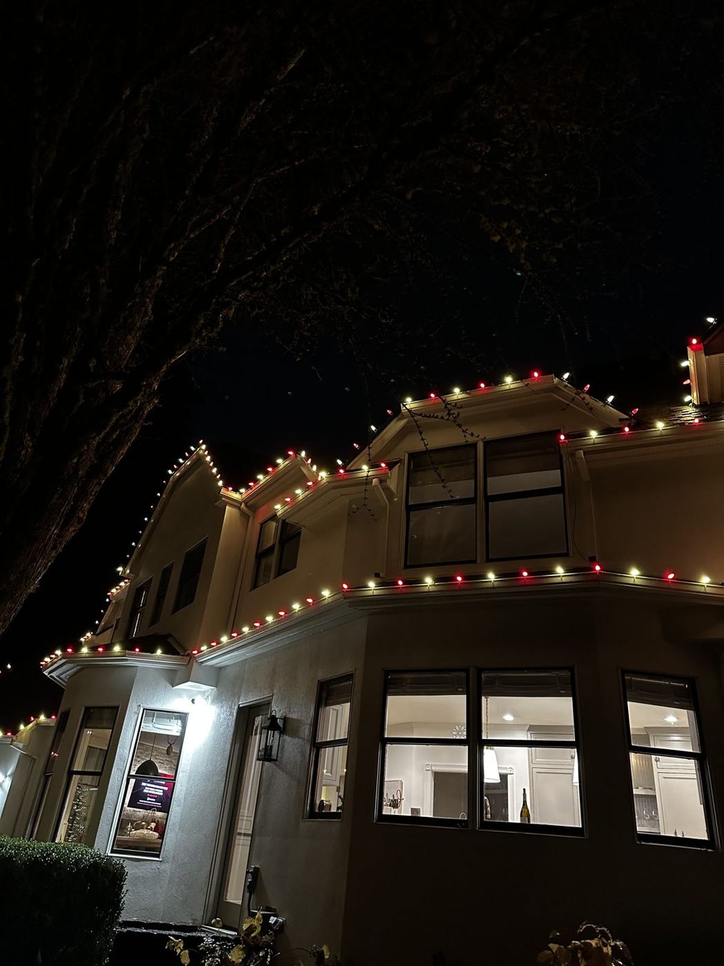 Two-story home with red and white candy-cane lights on the rooflines